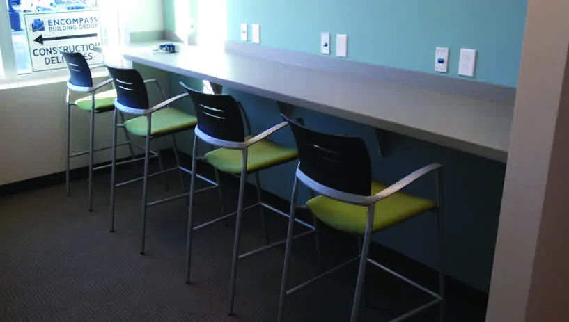 A row of tables with chairs and a wall